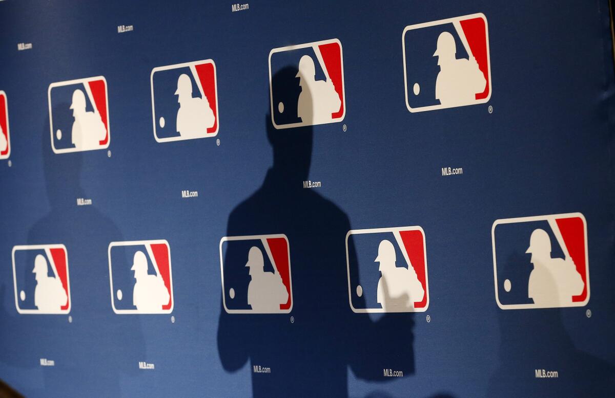 The shadow of MLB commissioner Rob Manfred is projected on an MLB logo backdrop.