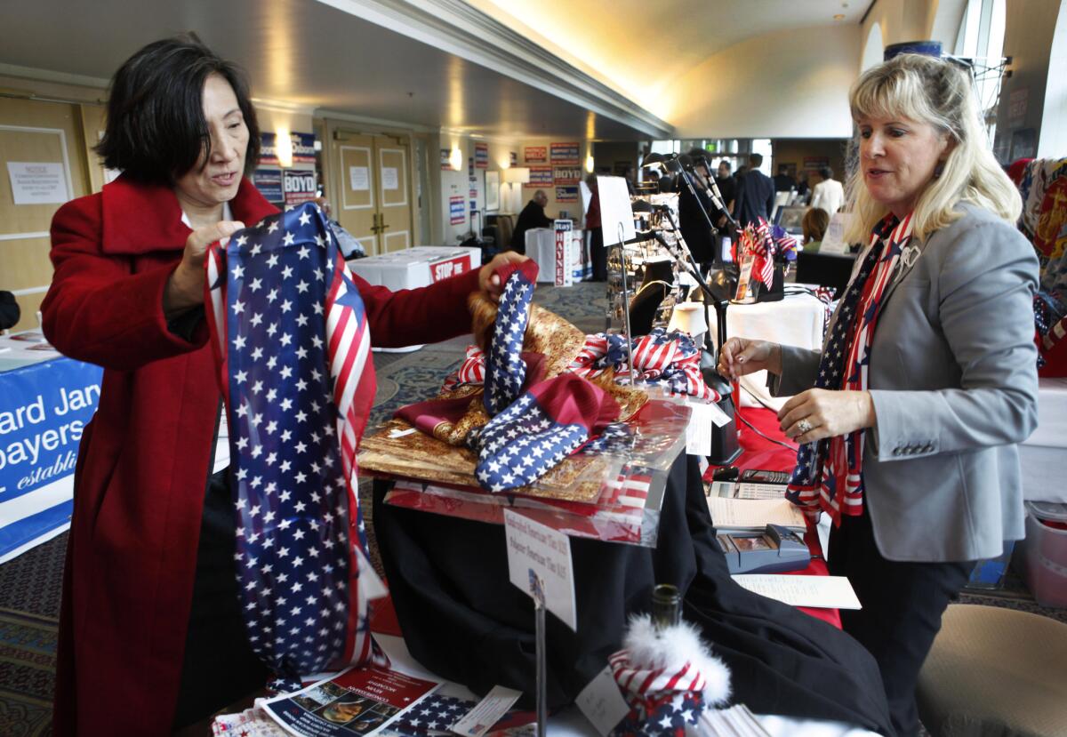 Helen Wang, left, looks at flag souvenirs at Kelley Slaught's Big Time Conservative American Store booth at the California Republican Convention in Sacramento in 2011.