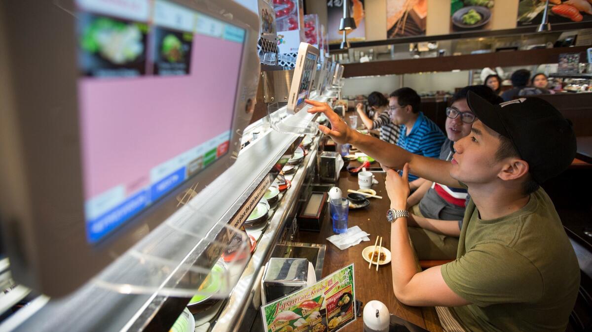 Thai Phi and Kenny Cheng from Toronto select their food from an electronic menu at the Kula Revolving Sushi Bar restaurant at Diamond Jamboree.