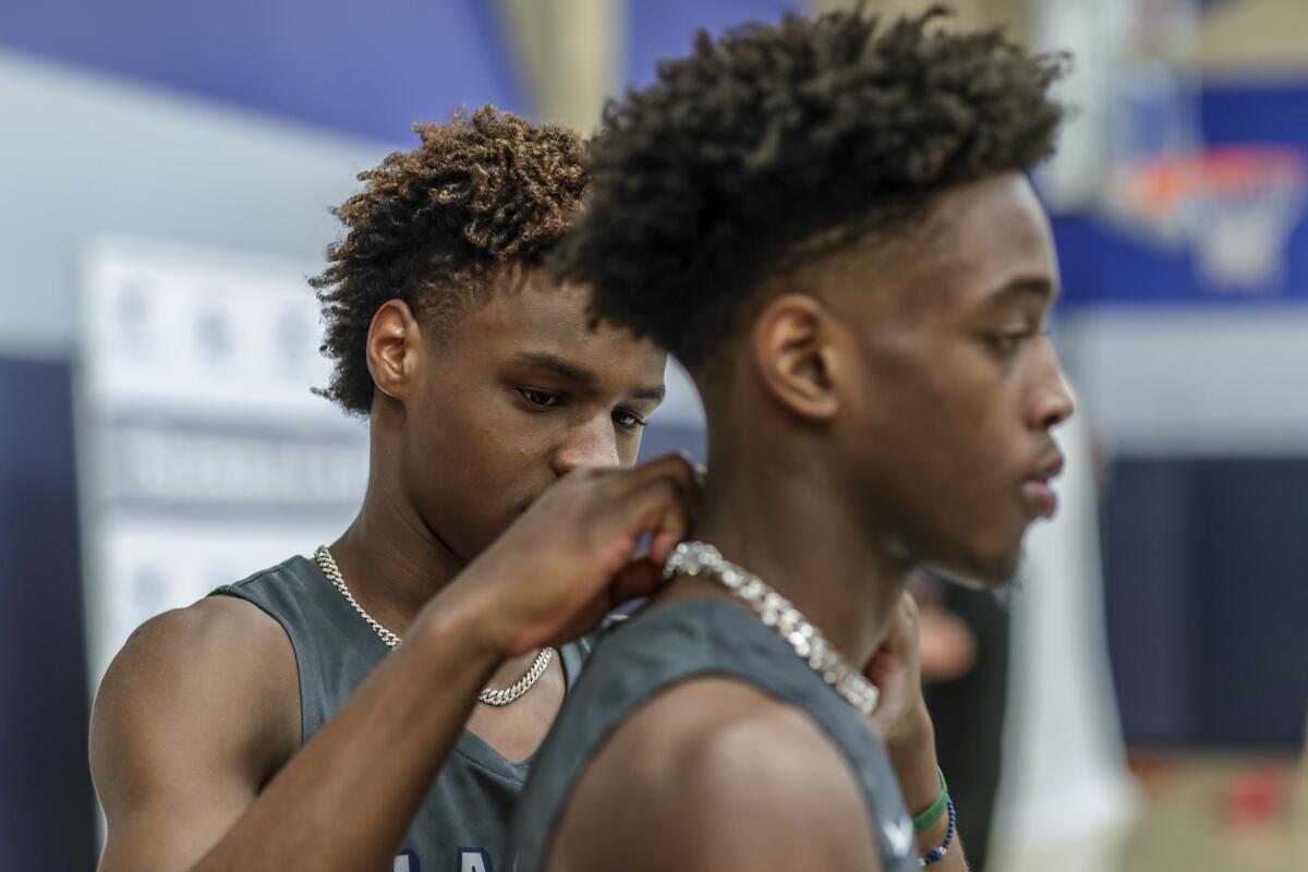 Bronny James adjusts a necklace on the neck of teammate Zaire Wade during Sierra Canyon High School basketball media day.
