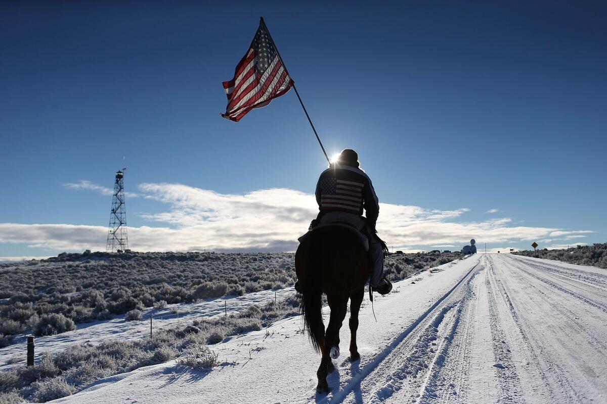 Duane Ehmer carries an American flag as he rides his horse, Hellboy, at the occupied Malheur National Wildlife Refuge on Jan. 15 near Burns, Ore.