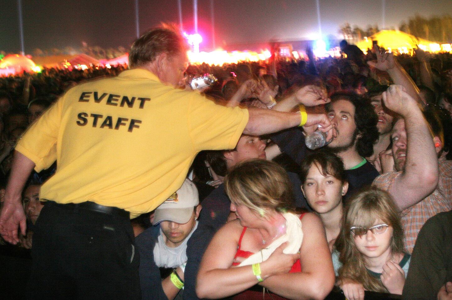 A guard passes water to a thirsty fan waiting for Coldplay to perform during the Coachella Valley Music and Arts Festival, 2005.