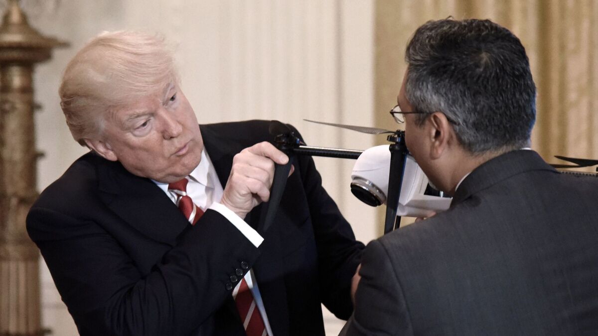 President Donald J. Trump holds a drone as George Mathew, CEO and Chairman of Kespry, explains how it works during an event at the White House in Washington on June 22.