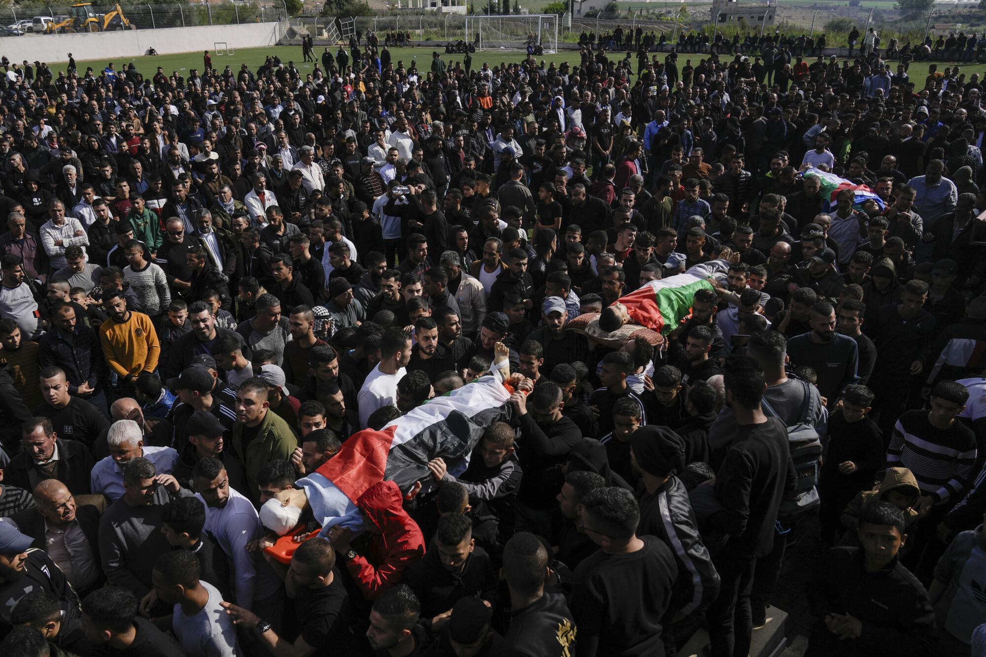 Mourners carrying bodies of Palestinians during their funeral in the West Bank
