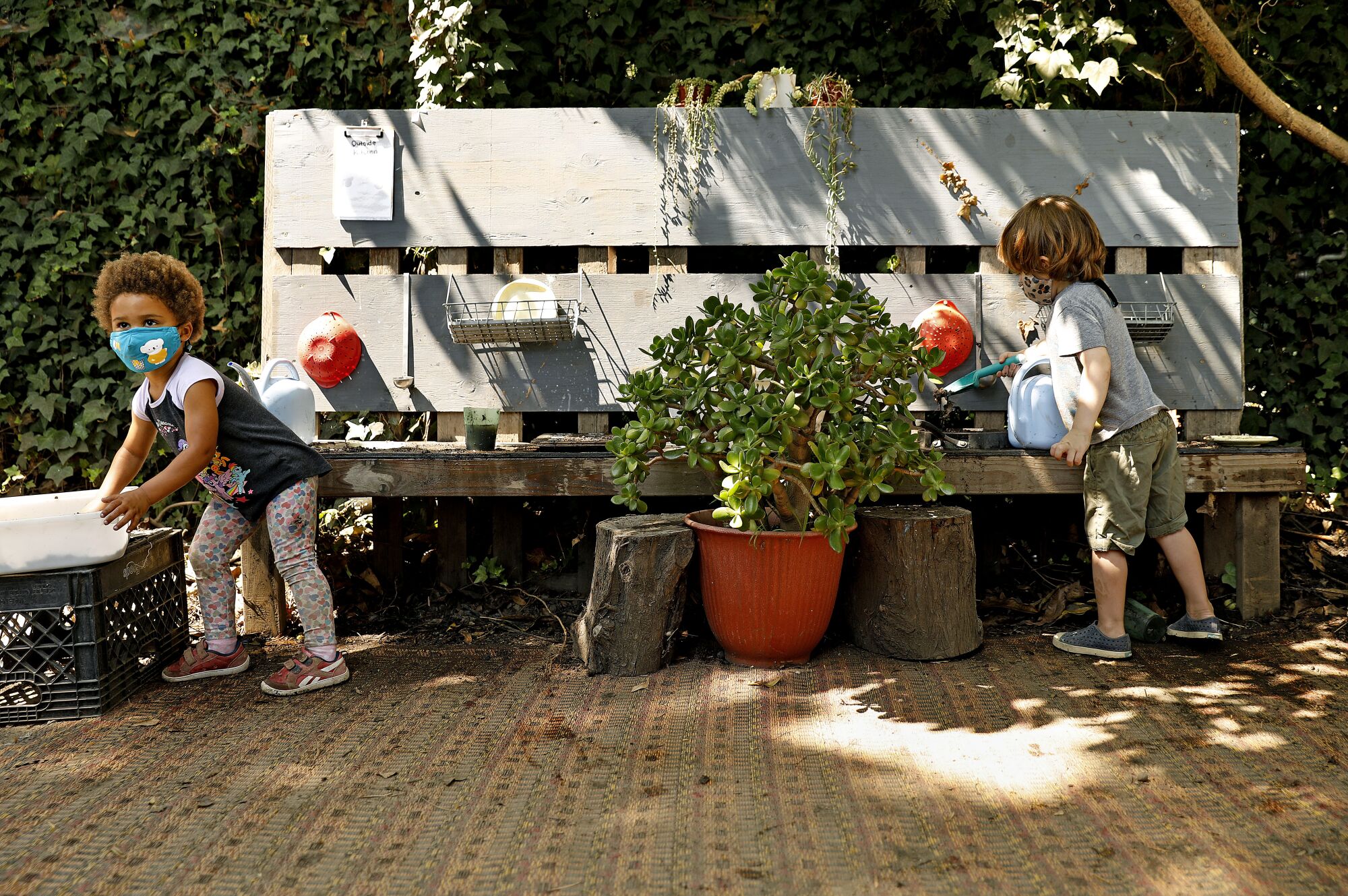Children socially distance while playing in an outdoor kitchen at Voyages Preschool.