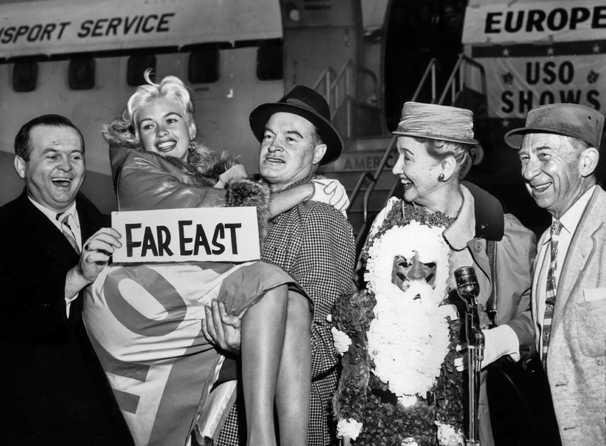 Dec. 16, 1957: Bob Hope gives actress Jayne Mansfield a lift as a USO troupe prepares to leave for overseas performances for the military. Johnny Grant, left, Hedda Hopper and Roscoe Ates look on.