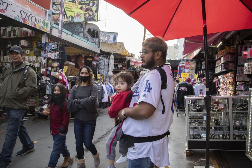 LOS ANGELES, CA - DECEMBER 20: Carlos Montiel and cousin Yaxiry (cq) Murrieta, 2, from Bakersfield visit Santee Alley on Monday, Dec. 20, 2021. Health officials are warning of a possible winter COVID surge with the Omicron variant. (Myung J. Chun / Los Angeles Times)