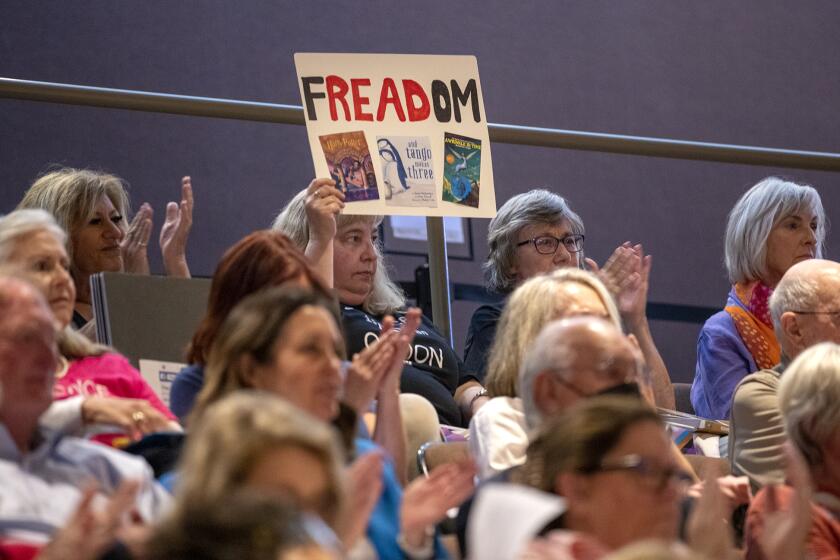 Huntington Beach, CA - June 20: An audience member holds a sing in opposition to Mayor pro tem Gracey Van Der Mark's agenda item that would filter out some books that she deems obscene or pornographic that are currently available to children at the city's public libraries, during a city council meeting on Tuesday, June 20, 2023 in Huntington Beach, CA. (Scott Smeltzer / Daily Pilot)