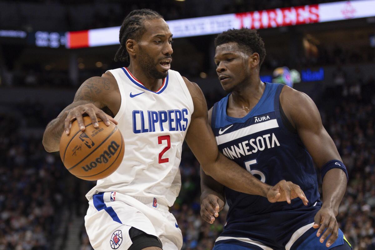 Clippers forward Kawhi Leonard, left, tries to drive around Timberwolves guard Anthony Edwards.