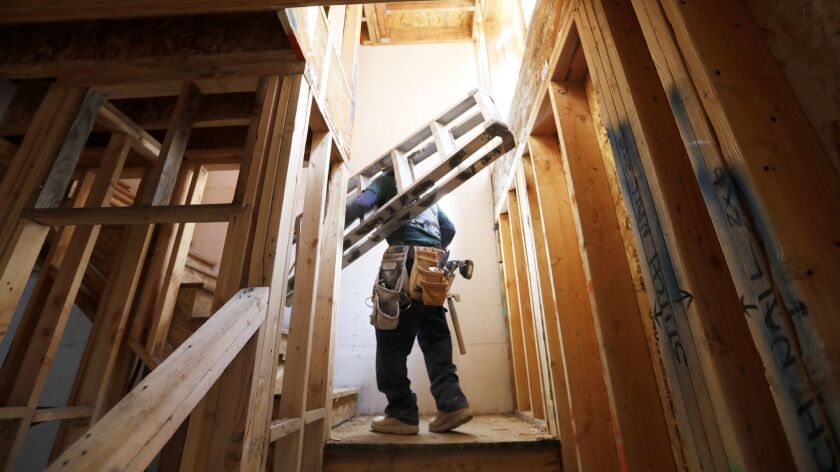 A worker carries a ladder up steps in a new home under construction in Bellflower in March. Construction jobs showed the most growth in California last month.
