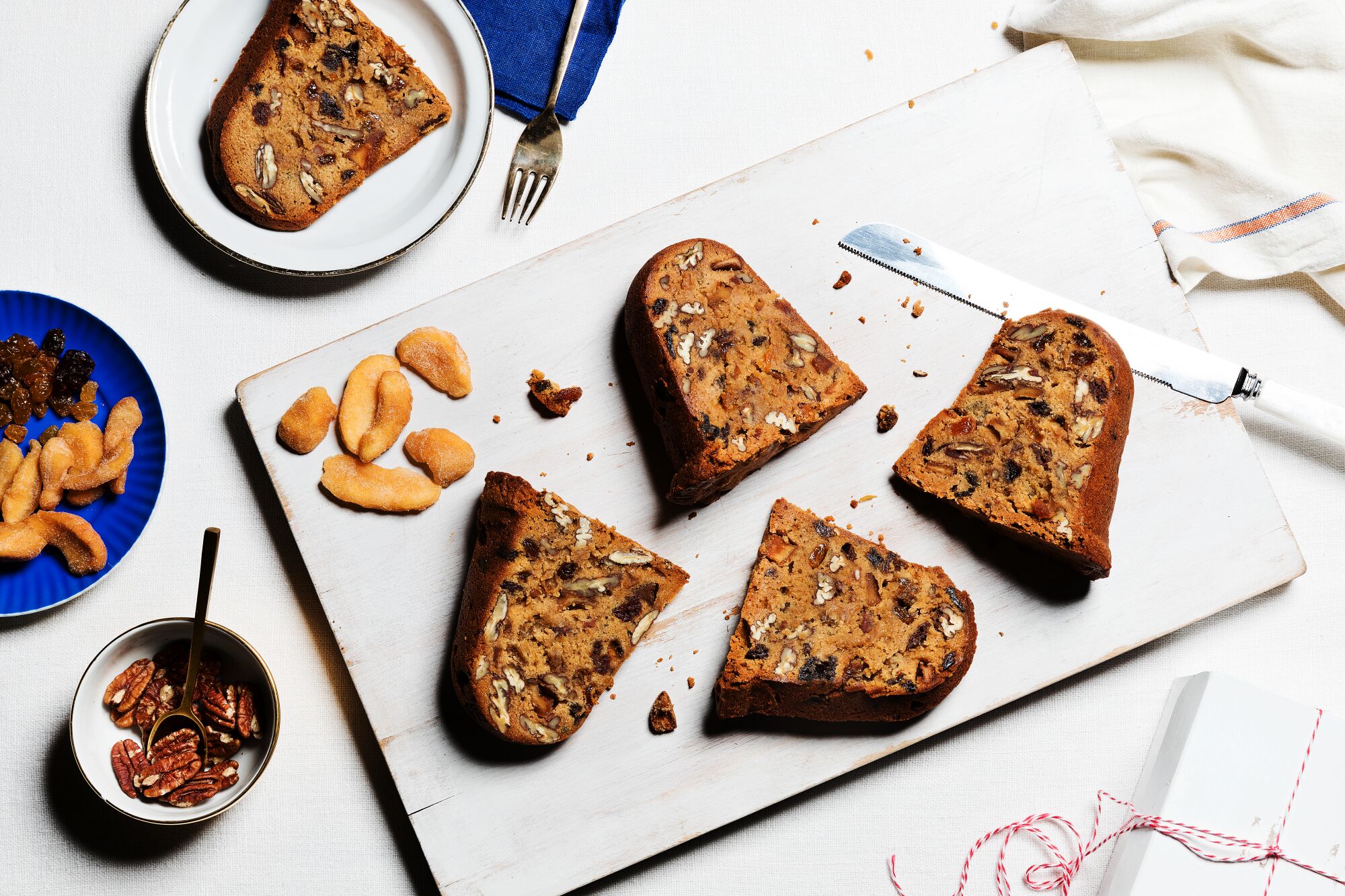 Slices of Cinnamon Holiday Cake With Bourbon, Dried Fruit and Pecans on a white cutting board