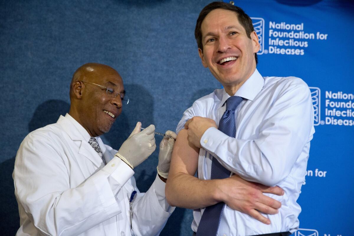 Dr. Tom Frieden, director of the U.S. Centers for Disease Control and Prevention, right, laughs as he receives a flu shot from nurse B.K. Morris in Washington.