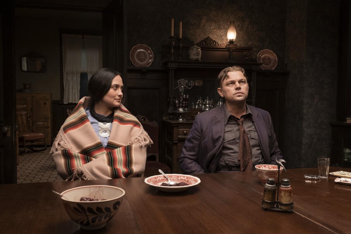 A woman and a man sitting at a dinner table with empty plates before them.