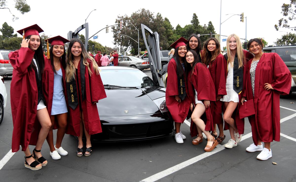 Estancia High School grads pose in front of a luxury vehicle at the end of the senior parade.