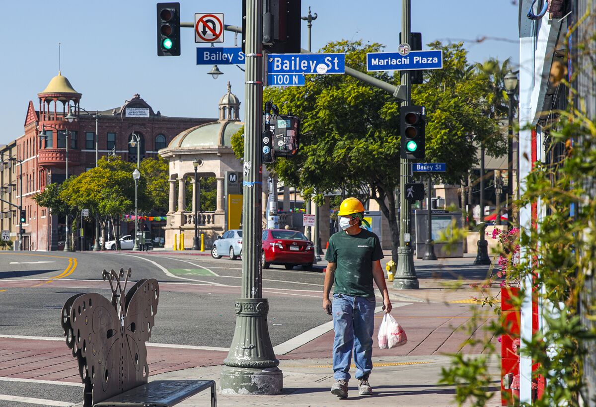 A worker crosses Mariachi Plaza at Bailey Street