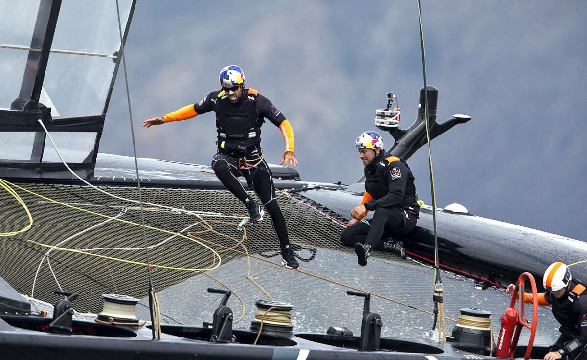 Shannon Falcone, left, a grinder for Oracle Team USA, wears a special sailing outfit -- including a Lycra suit, a homing beacon, high-top shoes and a crash helmet -- that weighs almost 16 pounds.