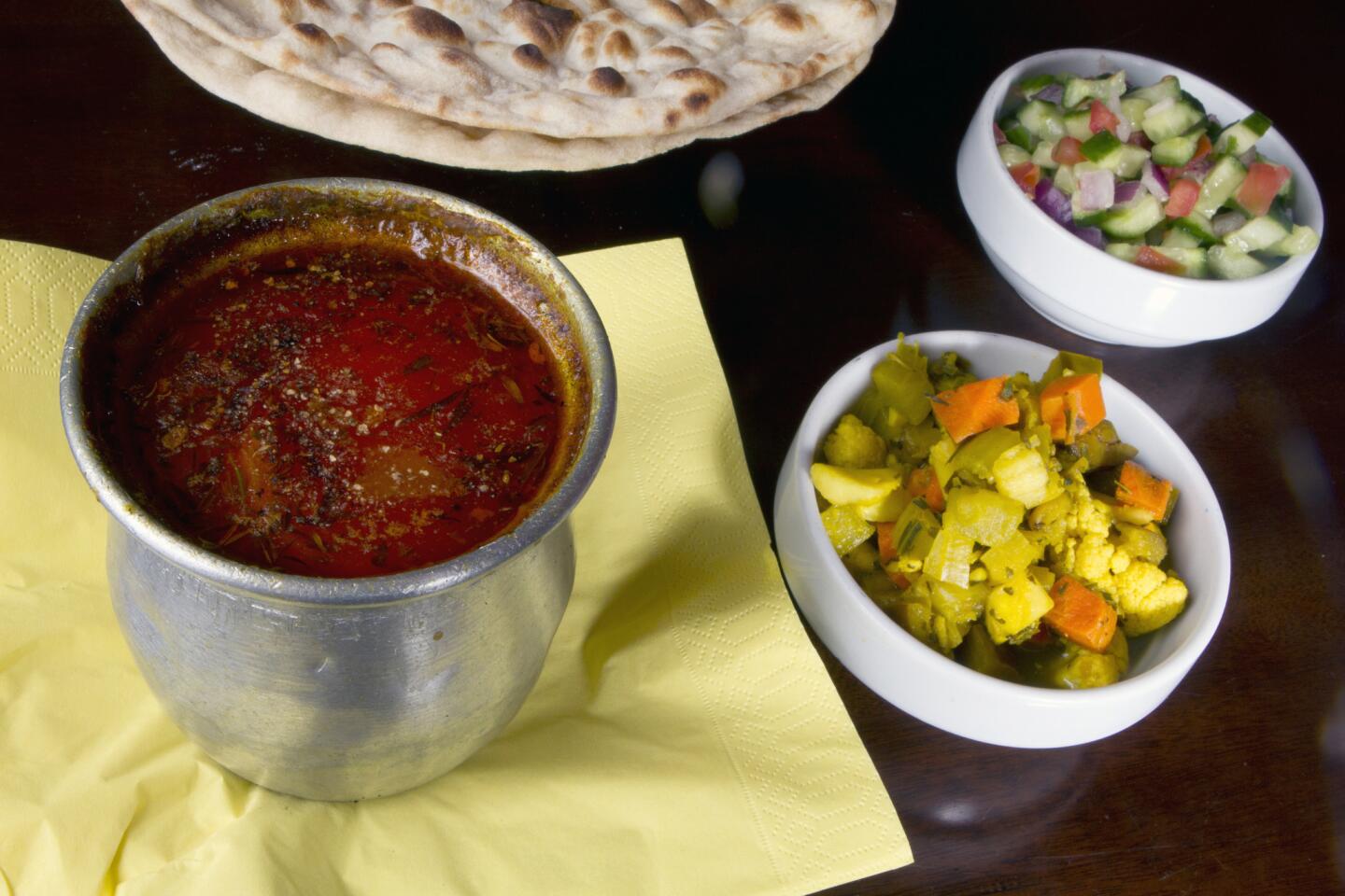 Dizi, left, a dish made with lamb meat, potato, tomato, turmeric and garbanzo and white beans baked in the oven for three hours, at Nersses Vanak Persian restaurant in Glendale.