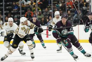 Boston Bruins right wing David Pastrnak, left, extends for the puck against Anaheim Ducks.