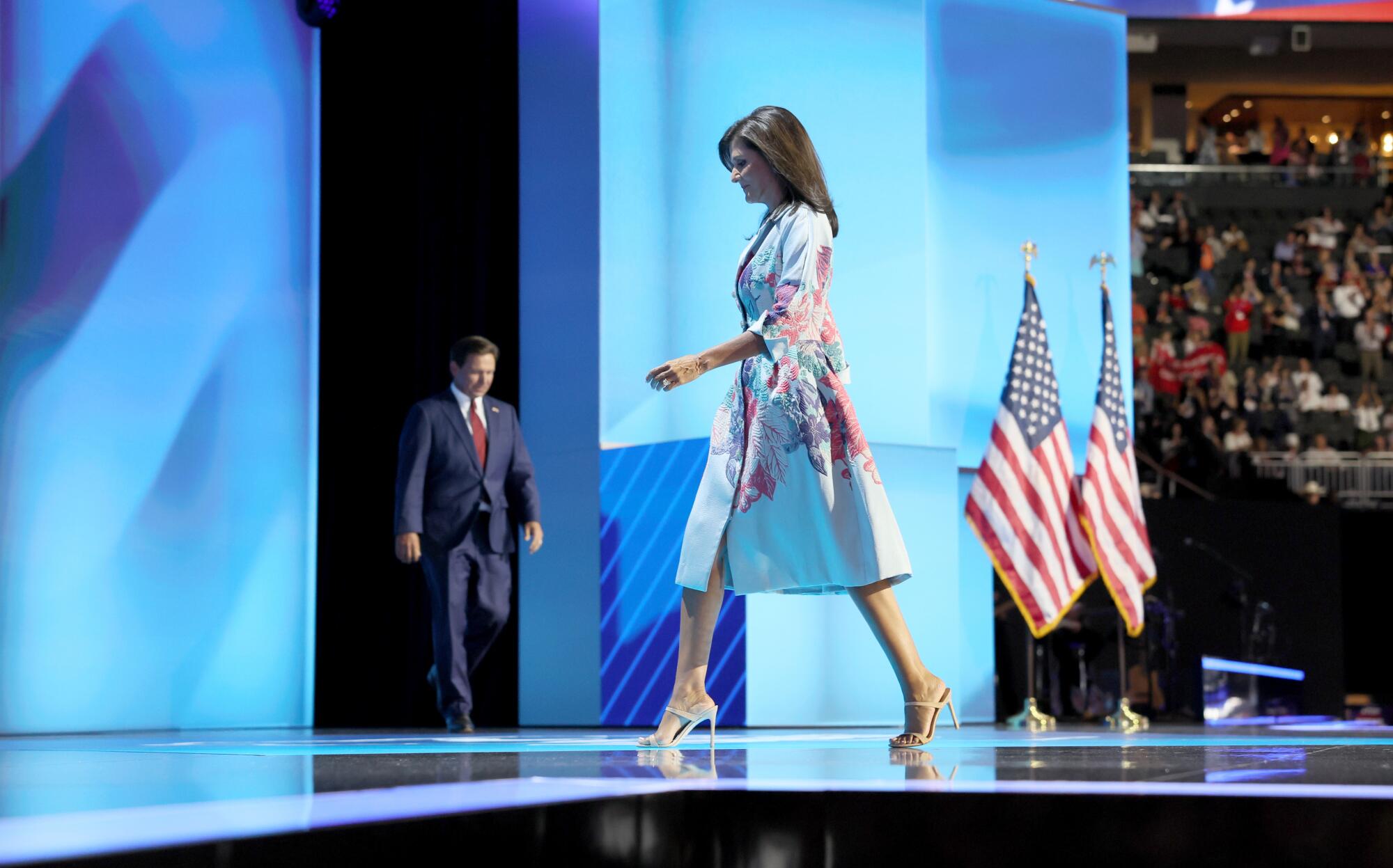 Former Ambassador Nikki Haley walks off the stage as Florida Gov. Ron DeSantis, back center, walks on at RNC.