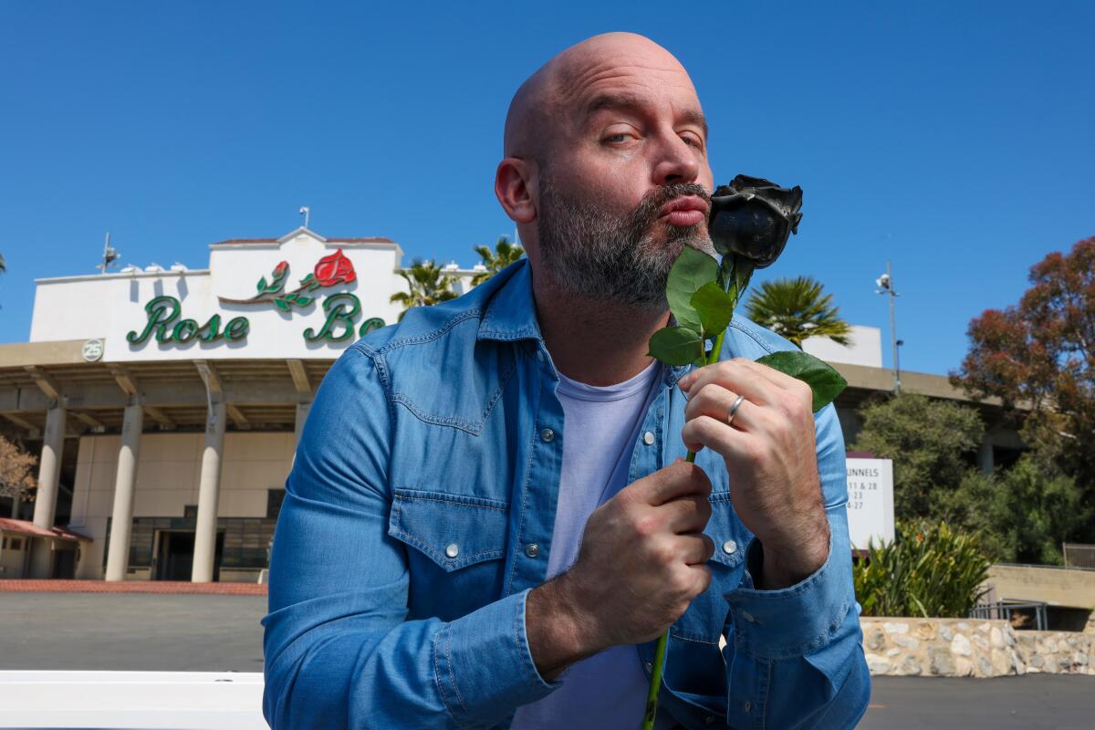 Man standing in front of the Rose Bowl holding a rose