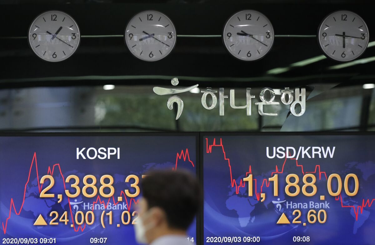 A currency trader walks near the screens showing the Korea Composite Stock Price Index (KOSPI), left, and the foreign exchange rate between U.S. dollar and South Korean won at the foreign exchange dealing room in Seoul, South Korea, Thursday, Sept. 3, 2020. Asian stock markets rose Thursday after Wall Street turned in its biggest daily gain since July despite uncertainty about the global outlook. (AP Photo/Lee Jin-man)