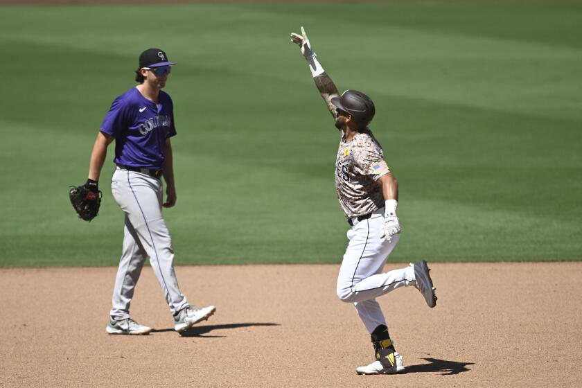 El venezolano de los Padres de San Diego, David Peralta (derecha) celebra luego de estremecer un jonrón de tres carreras, ante la mirada del primera base de los Rockies de Colorado, Michael Toglia (izquierda) durante el séptimo episodio del juego de béisbol el domingo 4 de agosto de 2024, en San Diego. (AP Foto/Denis Poroy)