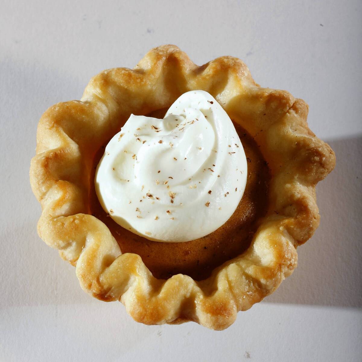 A pumpkin chiffon mini-pie is topped with whipped cream and nutmeg.