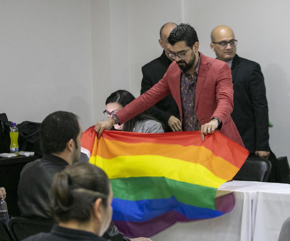 Fernando Urias, who was married to Victor Aguirre Espinoza during the first same-sex marriage in Baja California in 2015, places a gay pride flag on the front of the speakers tables before a workshop put on by the state government in Mexicali to discuss same-sex marriage rights.