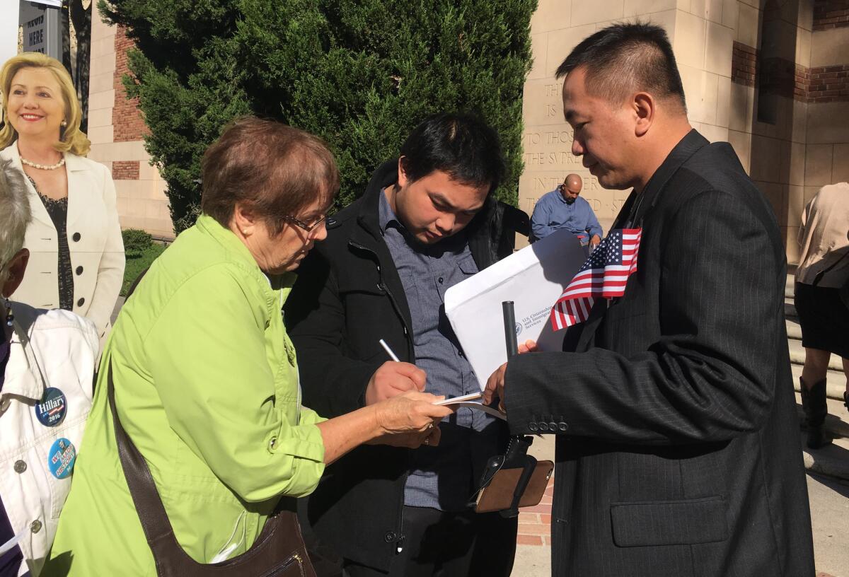 Thomas Macariola, center, fills out a voter registration form Oct. 26 after a naturalization ceremony in Sacramento.