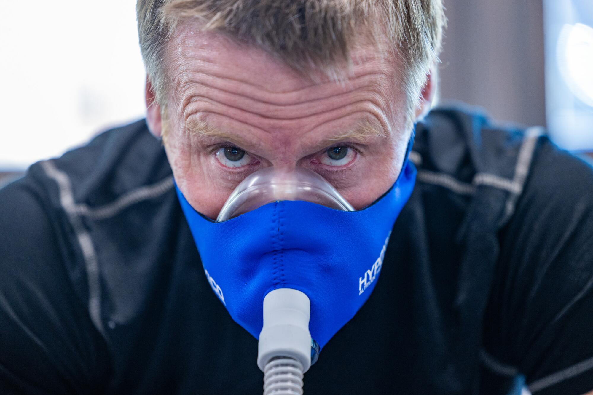 A man wears a blue air mask while exercising.