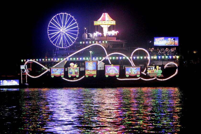 A large vessel decked out in a Christmas circus theme, moves along the route during the 111th Newport Beach Christmas Boat Parade on Wednesday evening.
