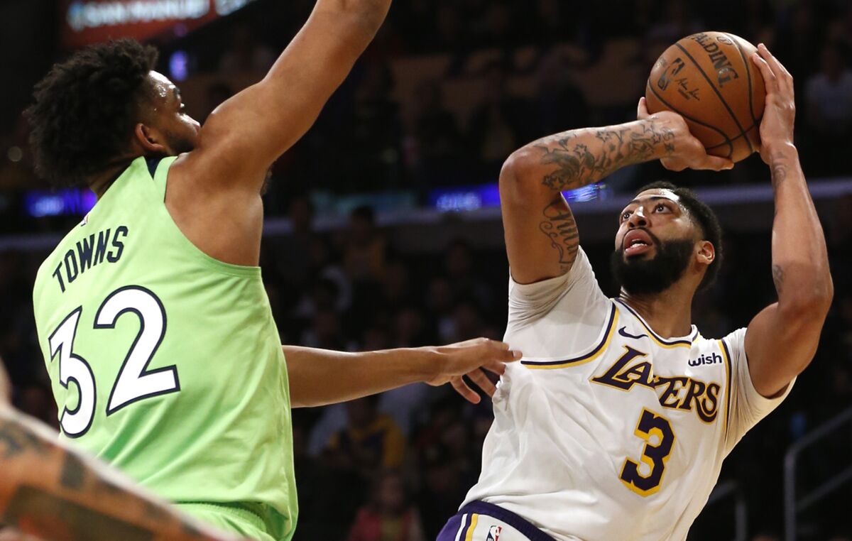 Anthony Davis takes a shot as Minnesota's Karl-Anthony Towns defends on Sunday at Staples Center.