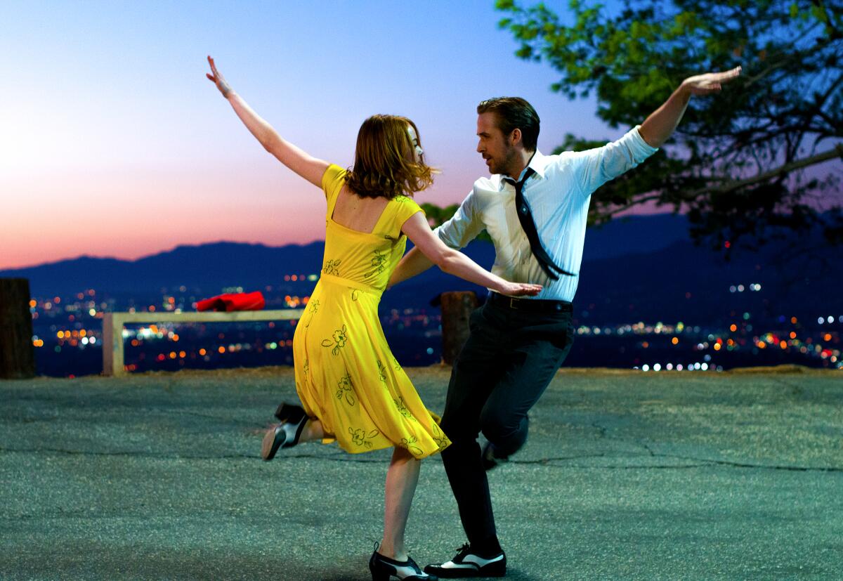 Emma Stone and Ryan Gosling dance in 'La La Land,' with the L.A. skyline behind them.