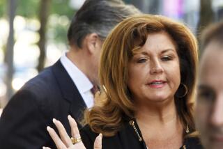 Abby Lee Miller waves with one manicured hand while arriving at a courthouse wearing a black outfit