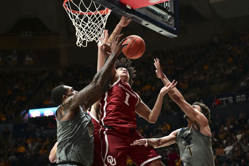 Oklahoma forward Jalen Hill (1) is guarded by West Virginia forward Jimmy Bell Jr. (15) and West Virginia forward Emmitt Matthews Jr. (1) during the second half of an NCAA college basketball game in Morgantown, W.Va., Saturday, Feb. 4, 2023. (AP Photo/William Wotring)