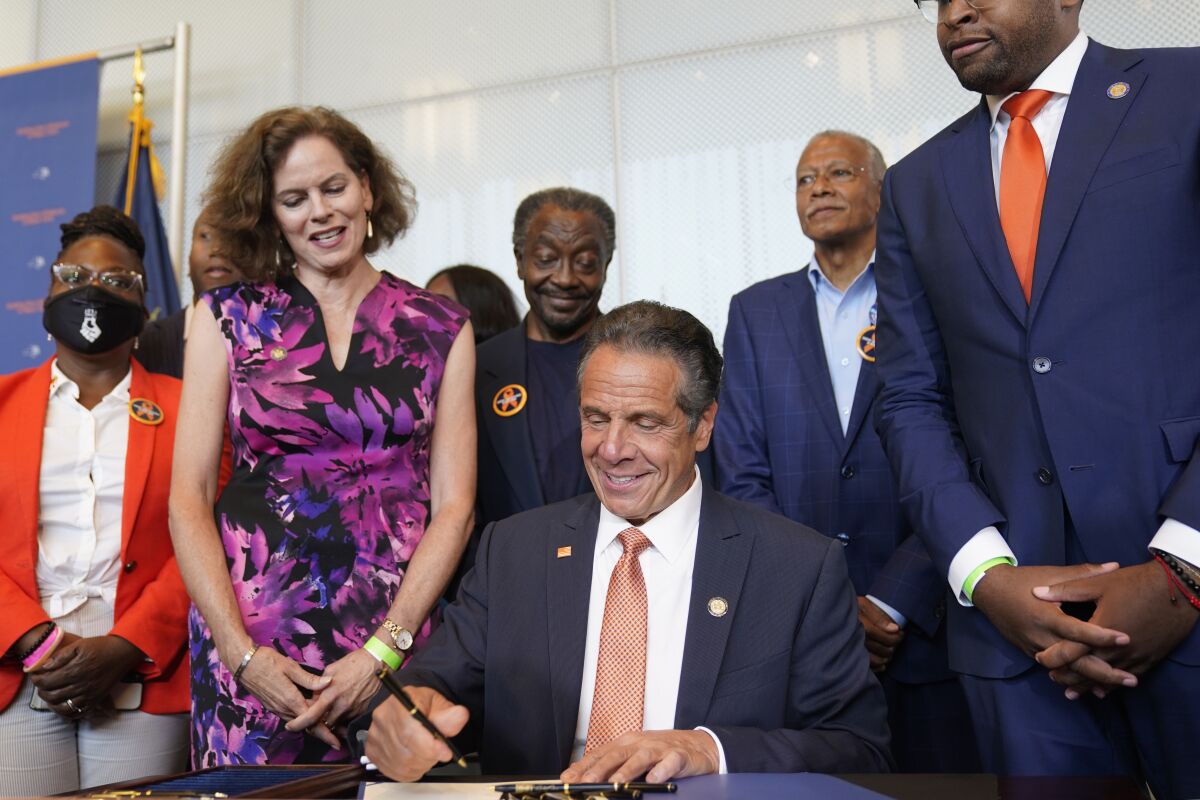 Surrounded by supporters and advocates, New York Governor Andrew Cuomo, center, signs legislation on gun control in New York, Tuesday, July 6, 2021. Cuomo signed two pieces of legislation to combat gun violence in New York state. (AP Photo/Seth Wenig)