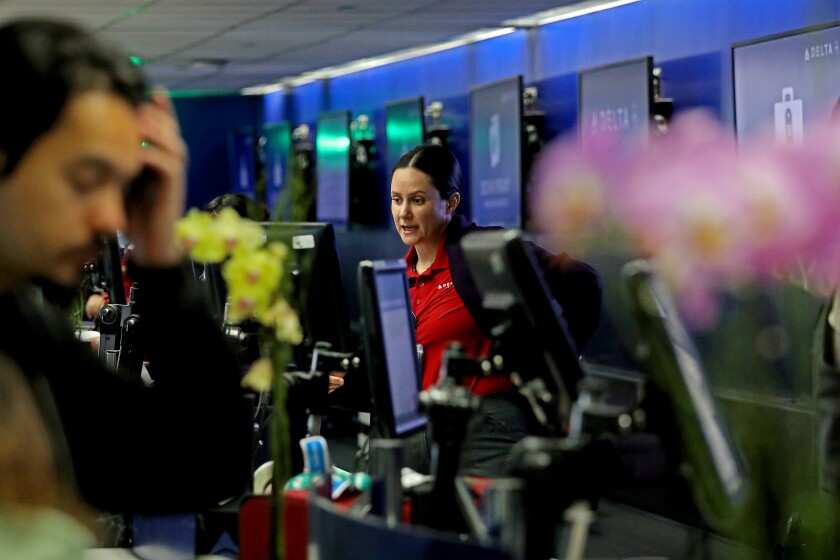 A ticket agent helps passengers at Delta Airlines Terminal Two