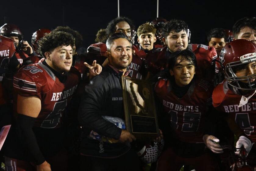 Sweetwater head coach Ervin Hernandez, center, poses for a photo with his team after beating St. Monica in a high school football game December, 2, 2023 in National City, Calif. (Photo by Denis Poroy)