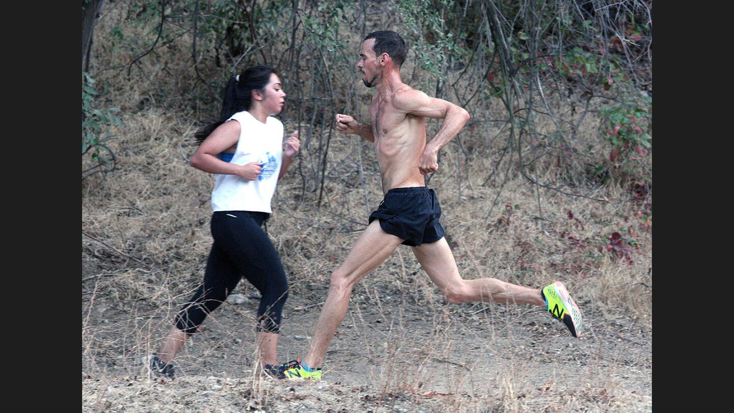 Leader in the 5k Jacques Sallberg runs toward the finish in the opposite direction of a runner who is heading up the hill at the Crescenta Valley Summer Race Series at Crescenta Valley Regional Park on Wednesday, August 9, 2017. 230 runners participated.