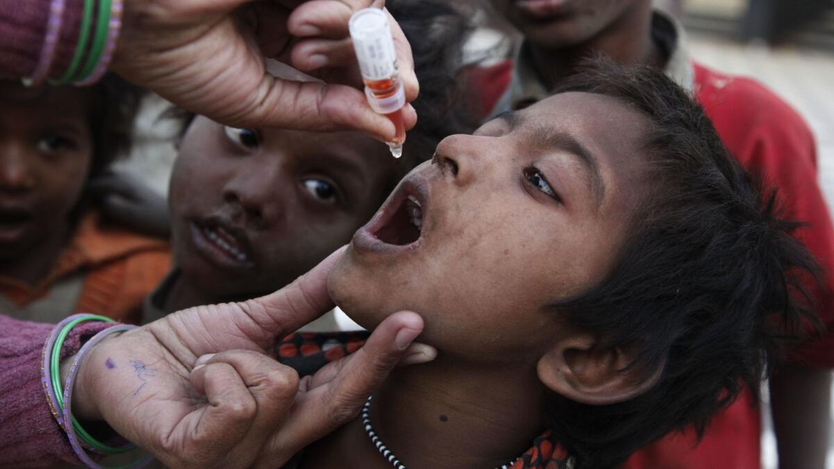 An Indian health worker administers a drop of polio vaccine to a homeless child at a railway station during a polio eradication campaign in Allahabad, India, in 2011.