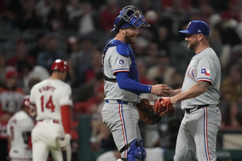 Rangers catcher Carson Kelly celebrates with pitcher Kirby Yates as the Angels walk off the field