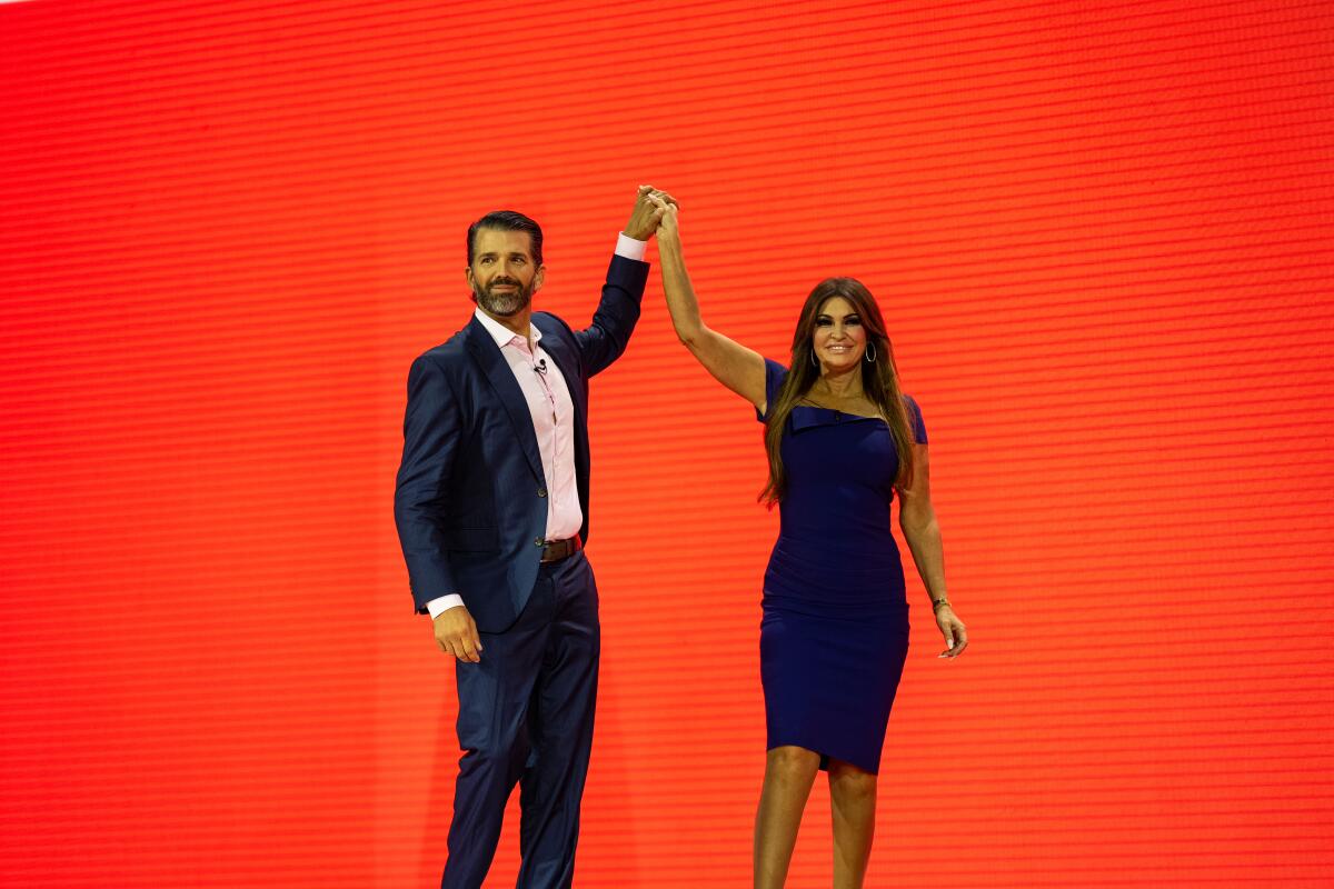 Donald Trump Jr. and Kimberly Guilfoyle hold hands above their heads onstage at CPAC
