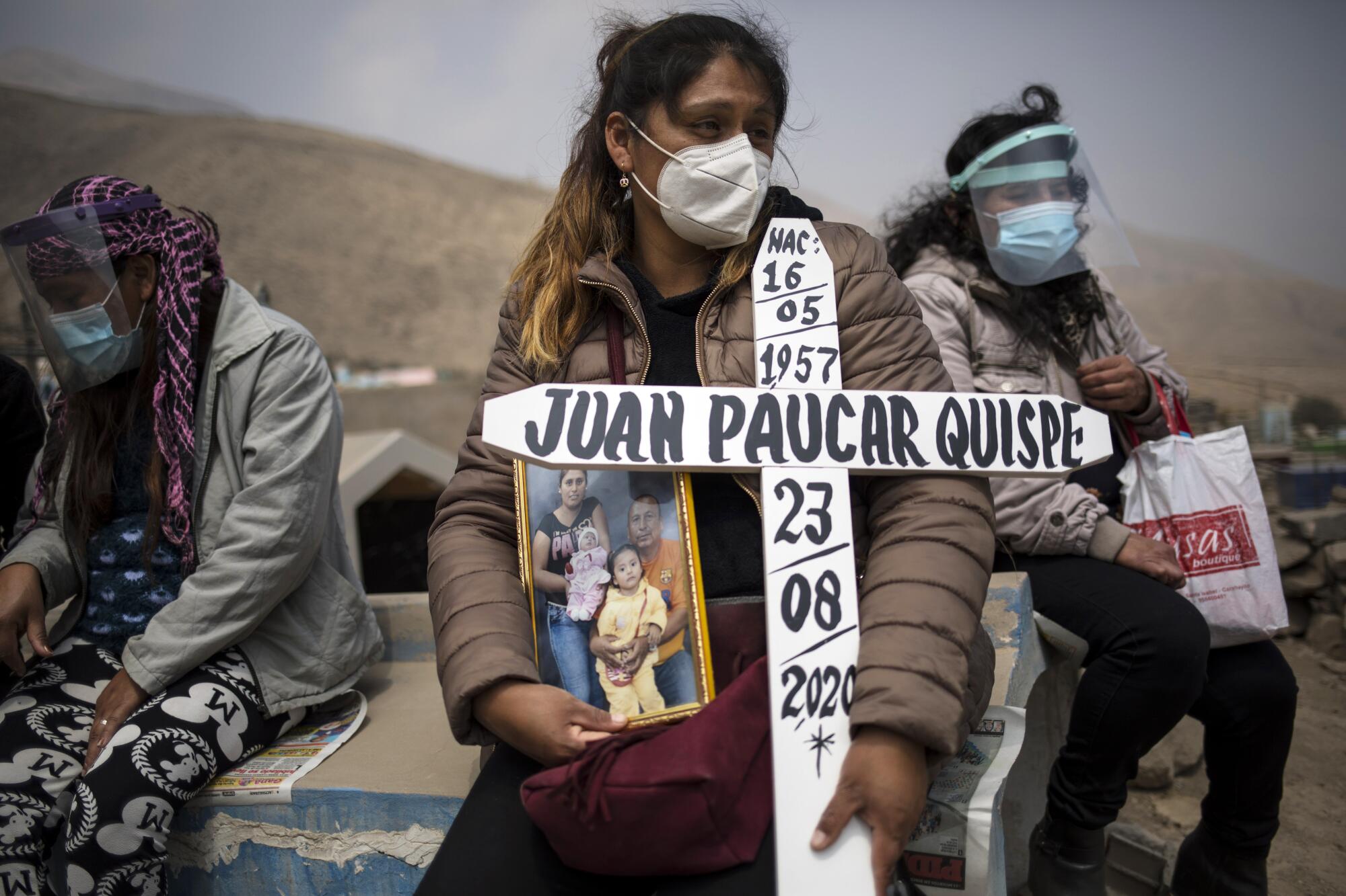 Ruth Morales waits for the arrival of the coffin of her husband, Juan Paucar Quispe, who died from COVID-19 complications