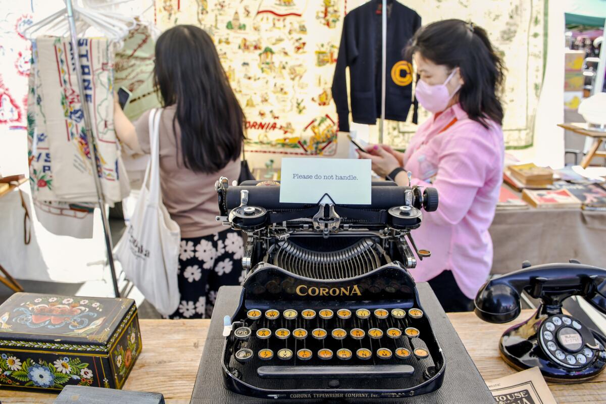 People shop for antiques at an outdoor flea market 