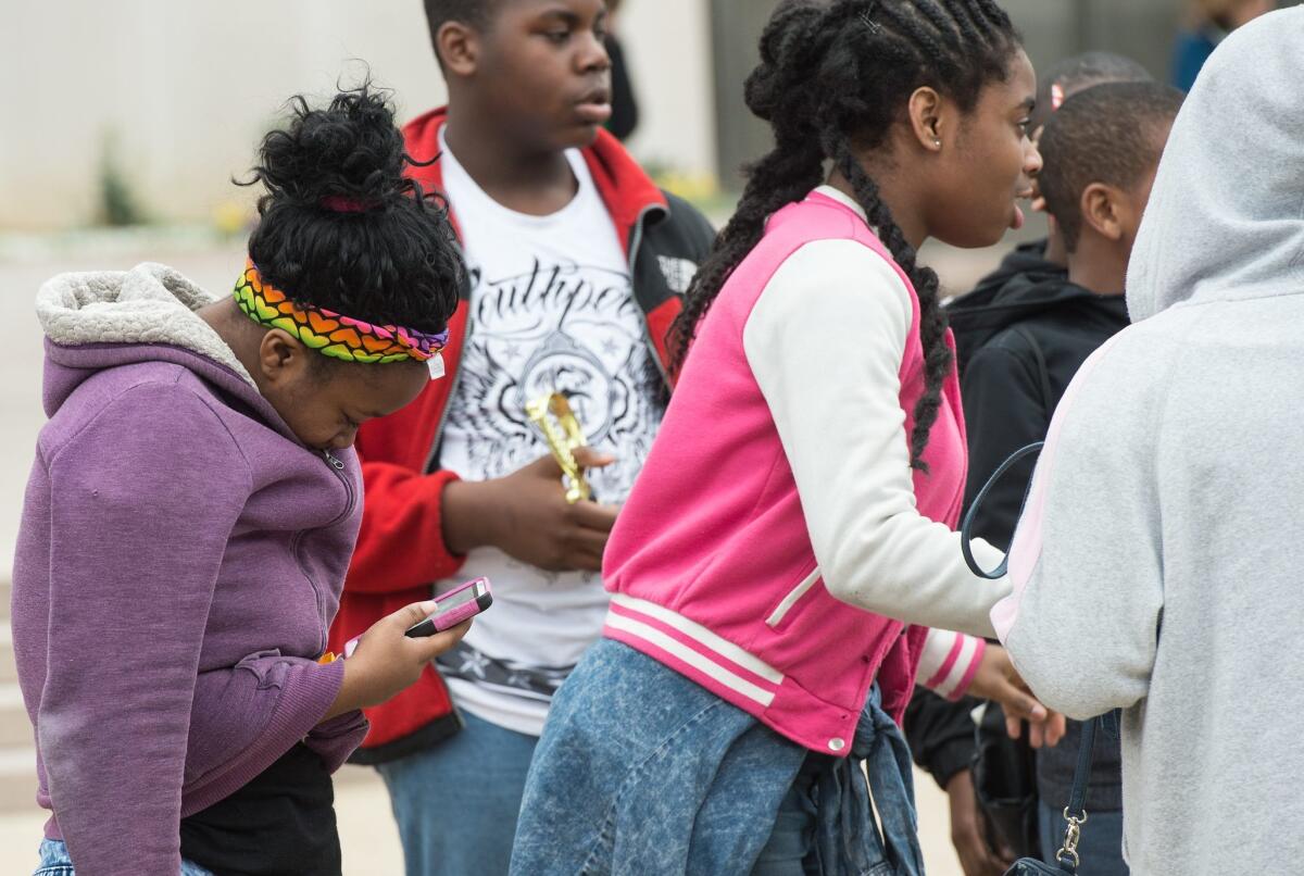 A teenager looks at her smartphone outside the Natural History Museum in Washington on April 8, 2015.