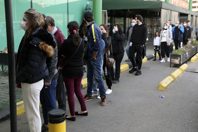 People line up to enter a supermarket, in Beirut, Lebanon, Monday, Jan. 11, 2021. Panic buyers swarmed supermarkets after reports the government planned to also order them shut in the tightened lockdown. Long lines formed outside chain supermarkets, sparking fear the crowds could further spread the virus. (AP Photo/Bilal Hussein)