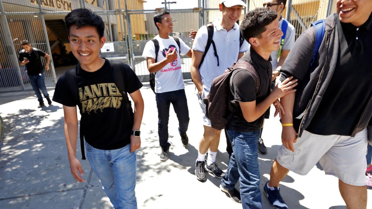 Noe Martinon, 18, left, walks through the campus of Santee Education Complex in Los Angeles.