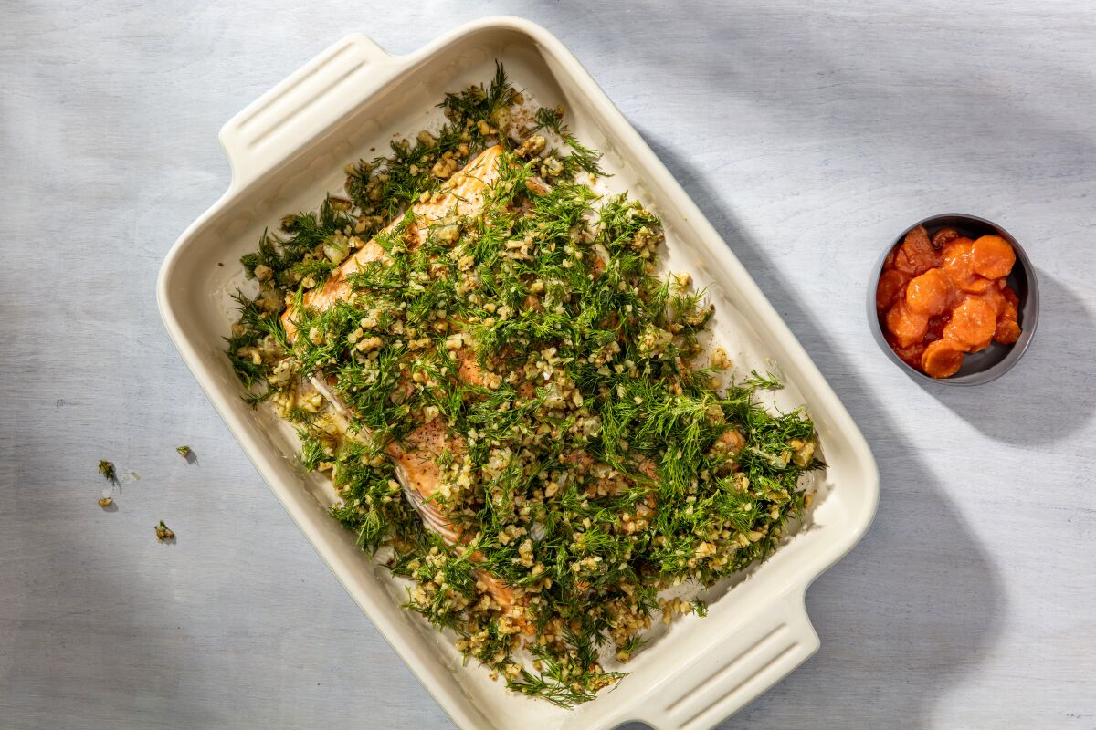 A dish of baked salmon topped with dill and lemon