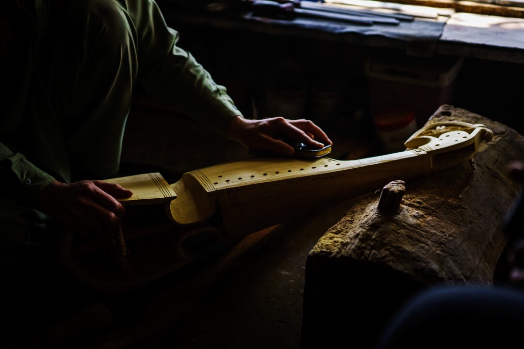 A man sands down the side of a rubab.