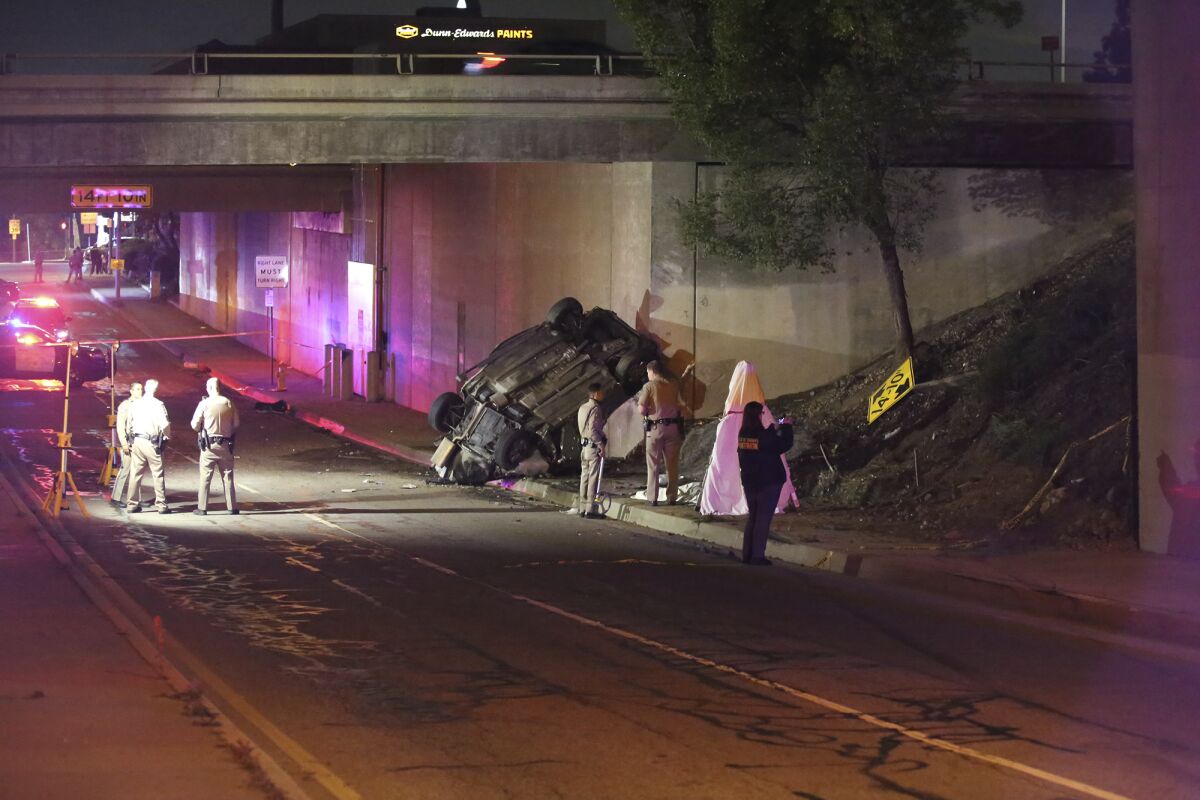 California Highway Patrol officers work at the scene of a fatal accident after the vehicle plunged off an elevated section of Interstate 210 landing below on Michillinda Ave., just south of Foothill Blvd., in Pasadena, Calif., late Sunday, Jan. 16, 2022. Two people in the car died at the scene and the third died at a hospital, KABC-TV reported. (AP Photo/James Carbone)